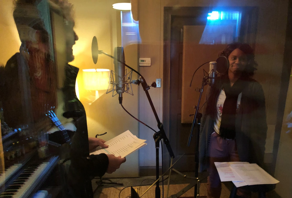 A man and woman singing in a recording booth